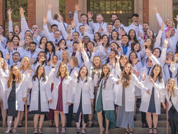Large gathering of current students in white coats