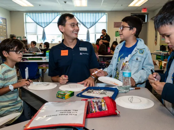 Pharmacy student guides elementary school youth through an activity. 