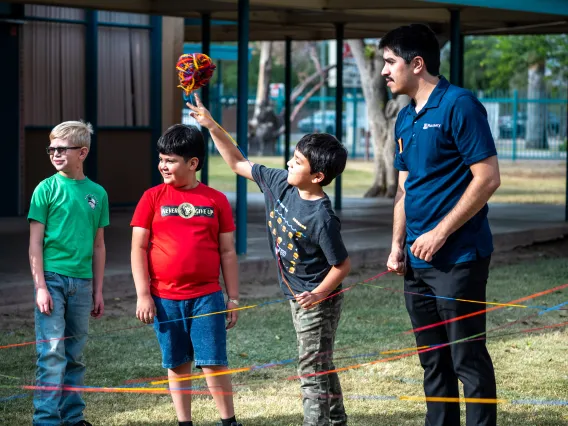 Elementary School Student throws a ball of yarn. 