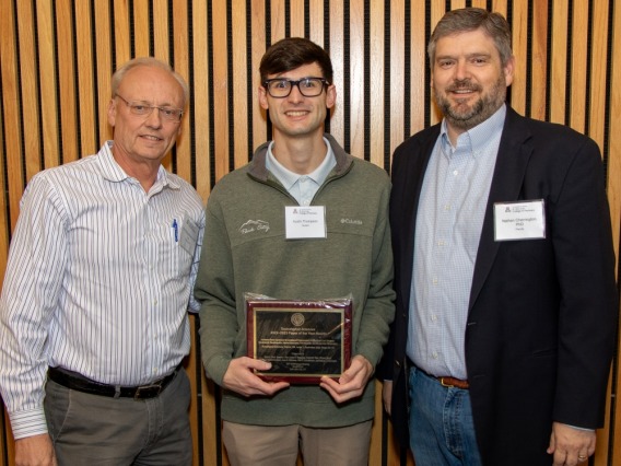 Dean Schnellmann and Dr. Nathan Cherrington stand with Austin Thompson, holding a plaque for Society of Toxicology Paper of the Year