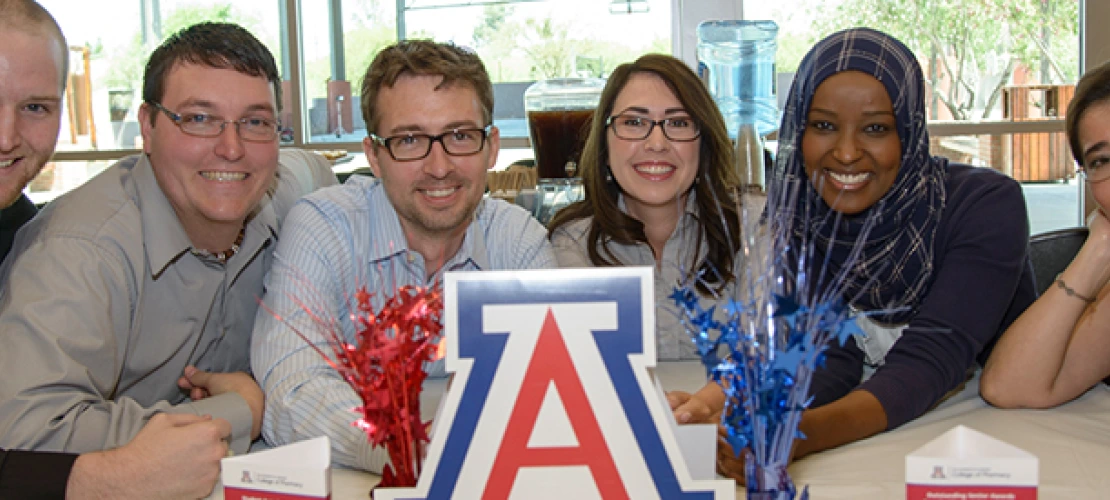 A group of students around the UofA sign
