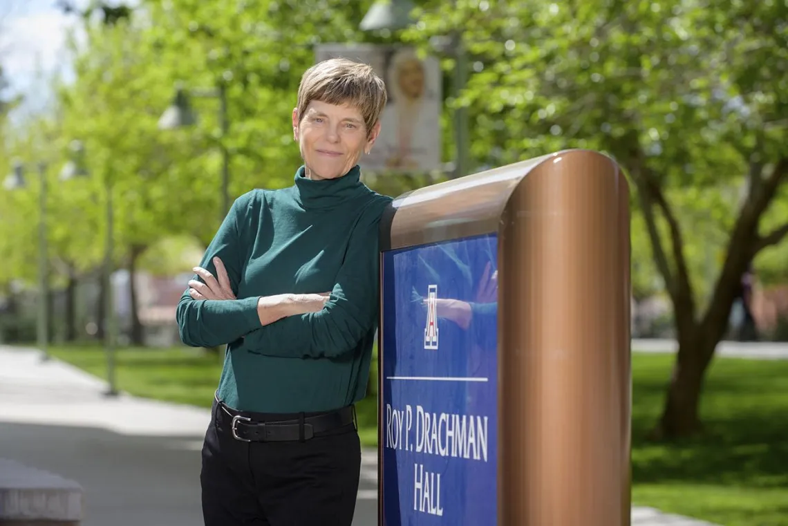 Woman leaning against a sign.
