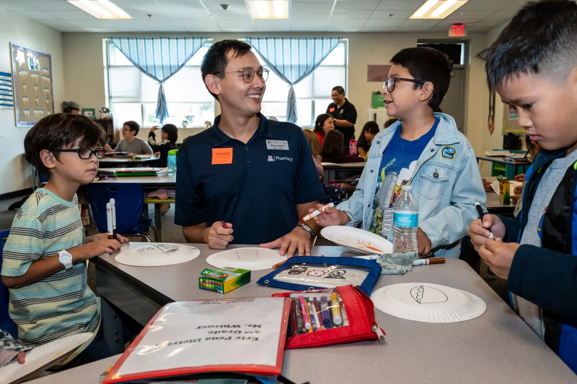 Pharmacy student guides elementary school youth through an activity.