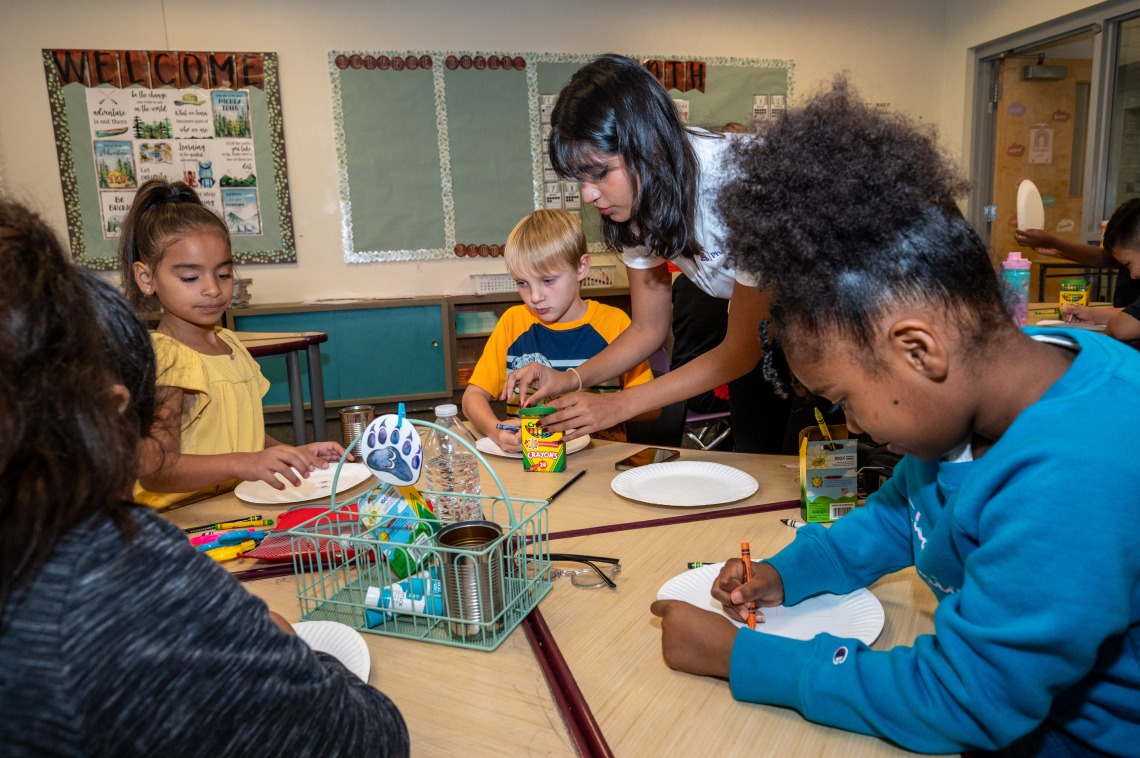 Pharmacy student guides young children through an health meal activity.