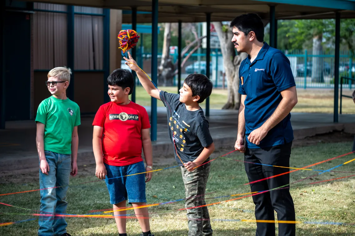 Elementary School Student throws a ball of yarn. 